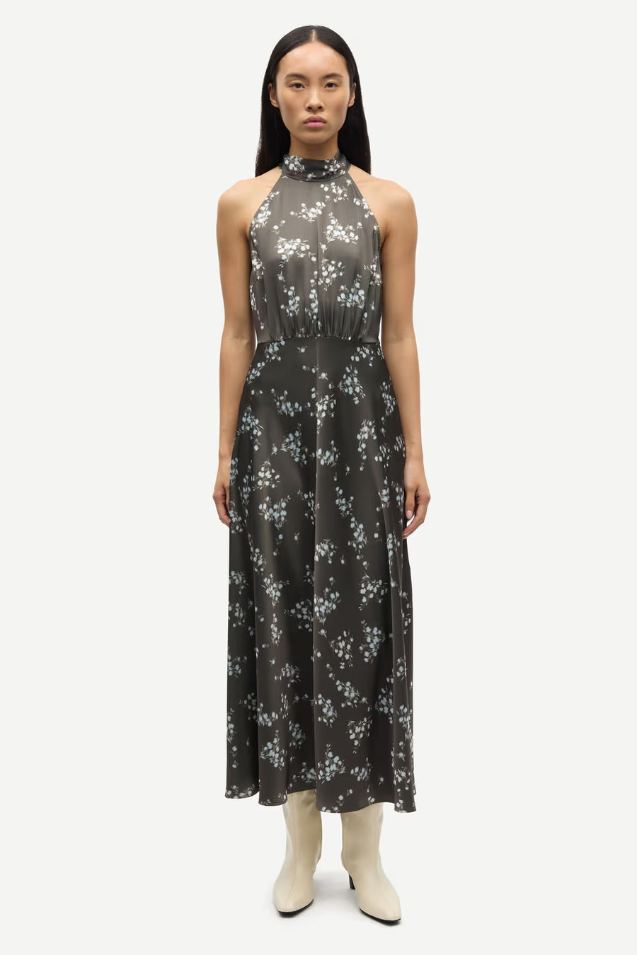 Woman wearing a sleeveless V-neck midi dress with a blue floral print and a tie waist, front view