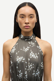 Woman wearing a sleeveless V-neck midi dress with a blue floral print and a tie waist, front detail