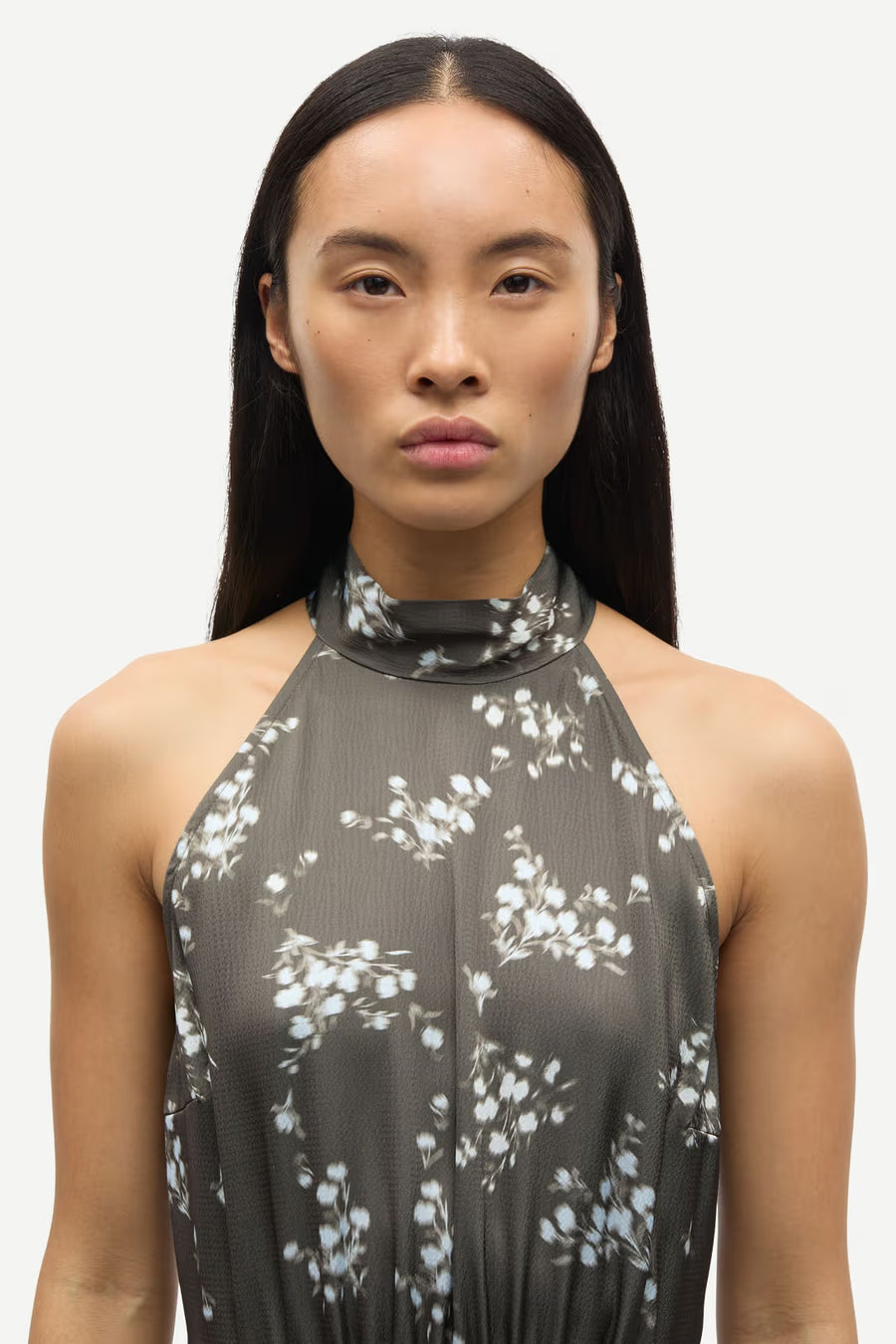 Woman wearing a sleeveless V-neck midi dress with a blue floral print and a tie waist, front detail