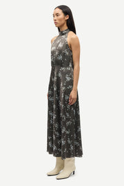 Woman wearing a sleeveless V-neck midi dress with a blue floral print and a tie waist, side