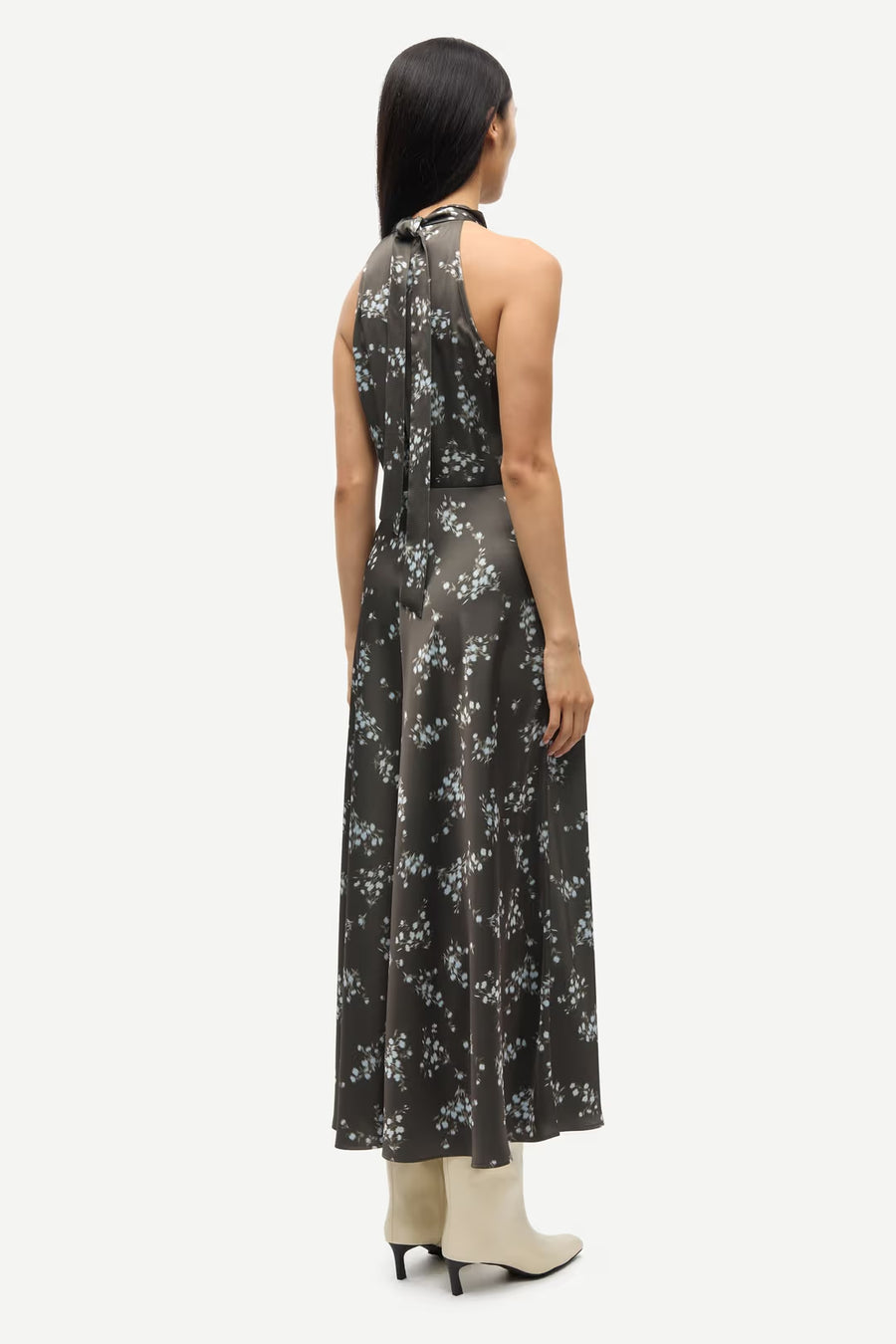 Woman wearing a sleeveless V-neck midi dress with a blue floral print and a tie waist, back