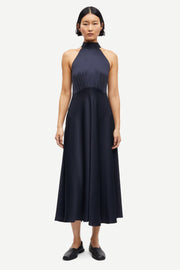 Woman wearing a navy sleeveless halter-neck midi dress with a fitted bodice and flared skirt, front view