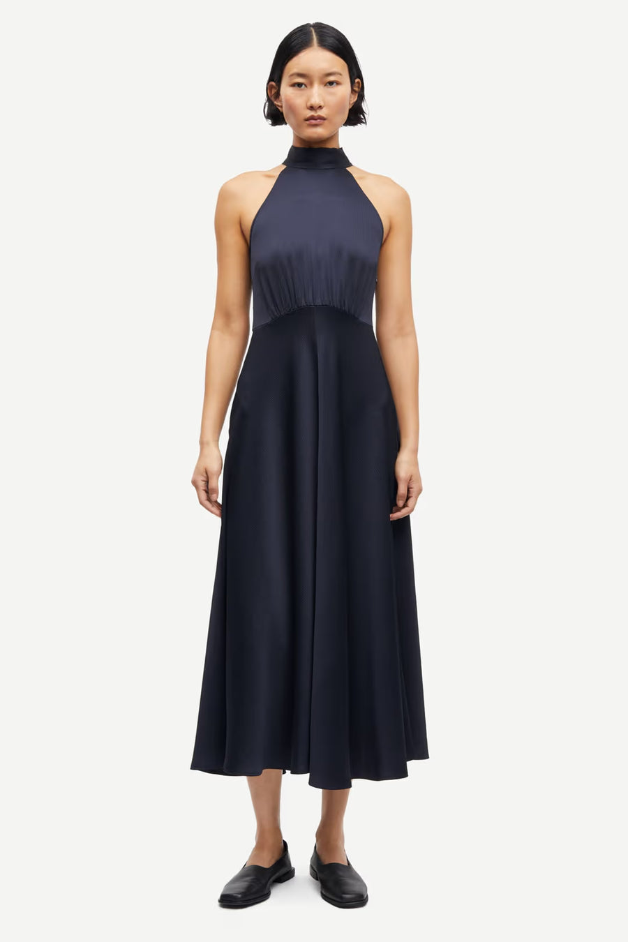 Woman wearing a navy sleeveless halter-neck midi dress with a fitted bodice and flared skirt, front view