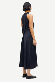 Woman wearing a navy sleeveless halter-neck midi dress with a fitted bodice and flared skirt, side view