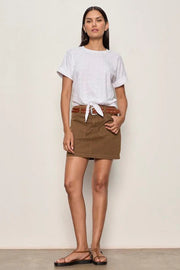 Woman wearing a brown,  denim, front pockets, mini skirt