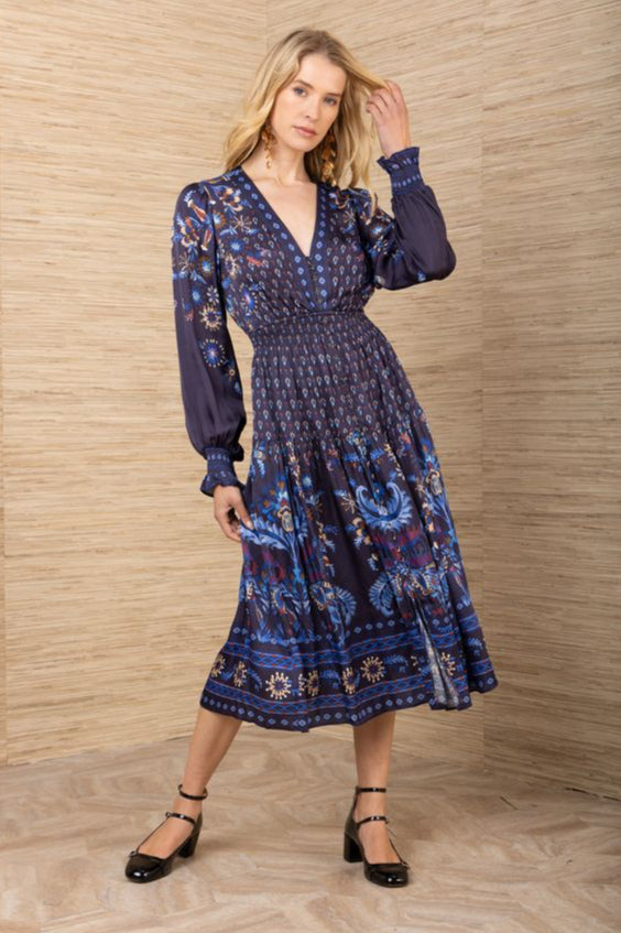 Front full body view of woman wearing a patterned navy blue long sleeve midi dress
