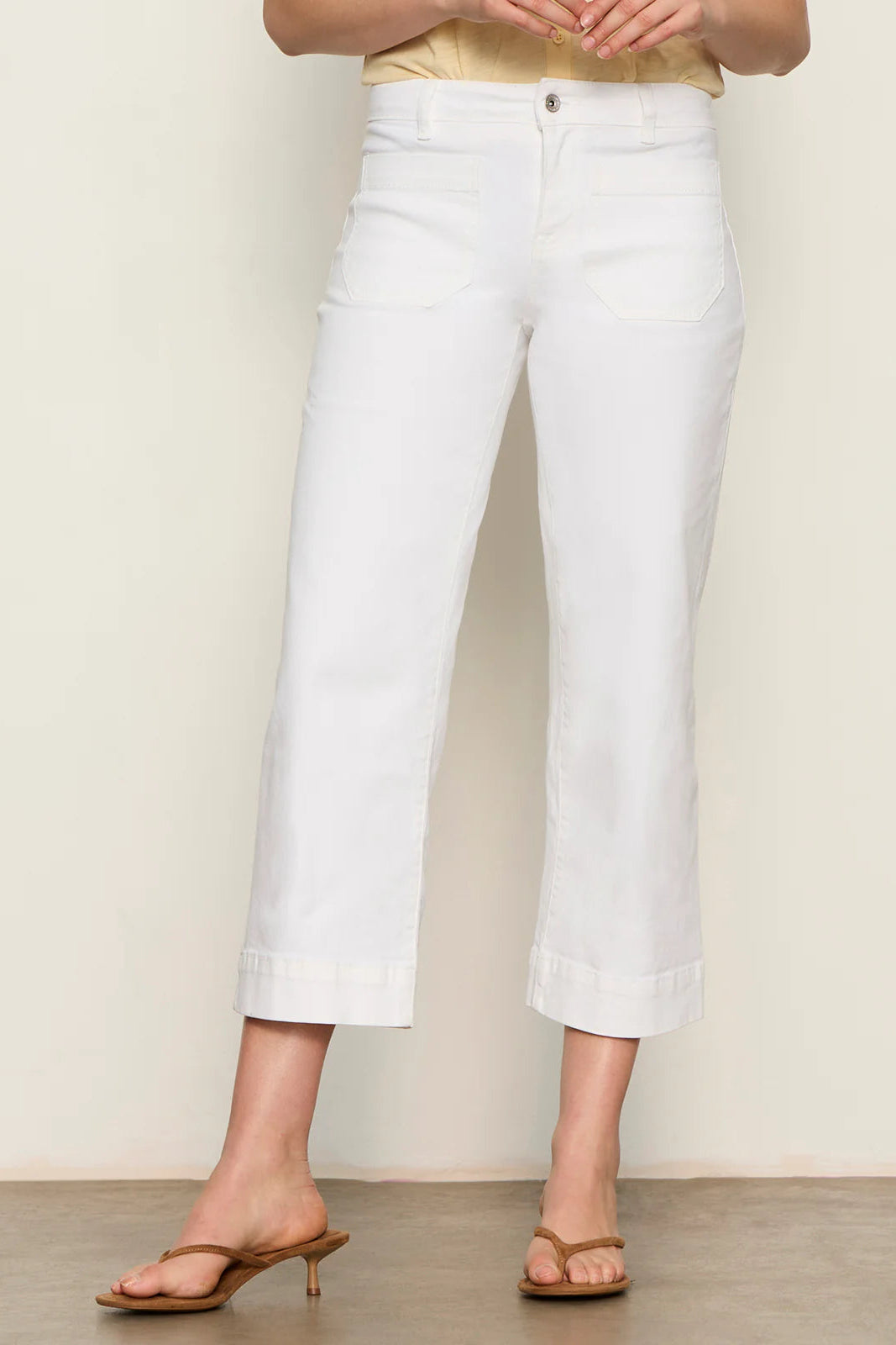 Woman wearing white high-waisted cropped straight-leg pants, front