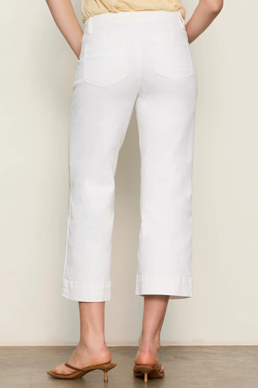 Woman wearing white high-waisted cropped straight-leg pants, back