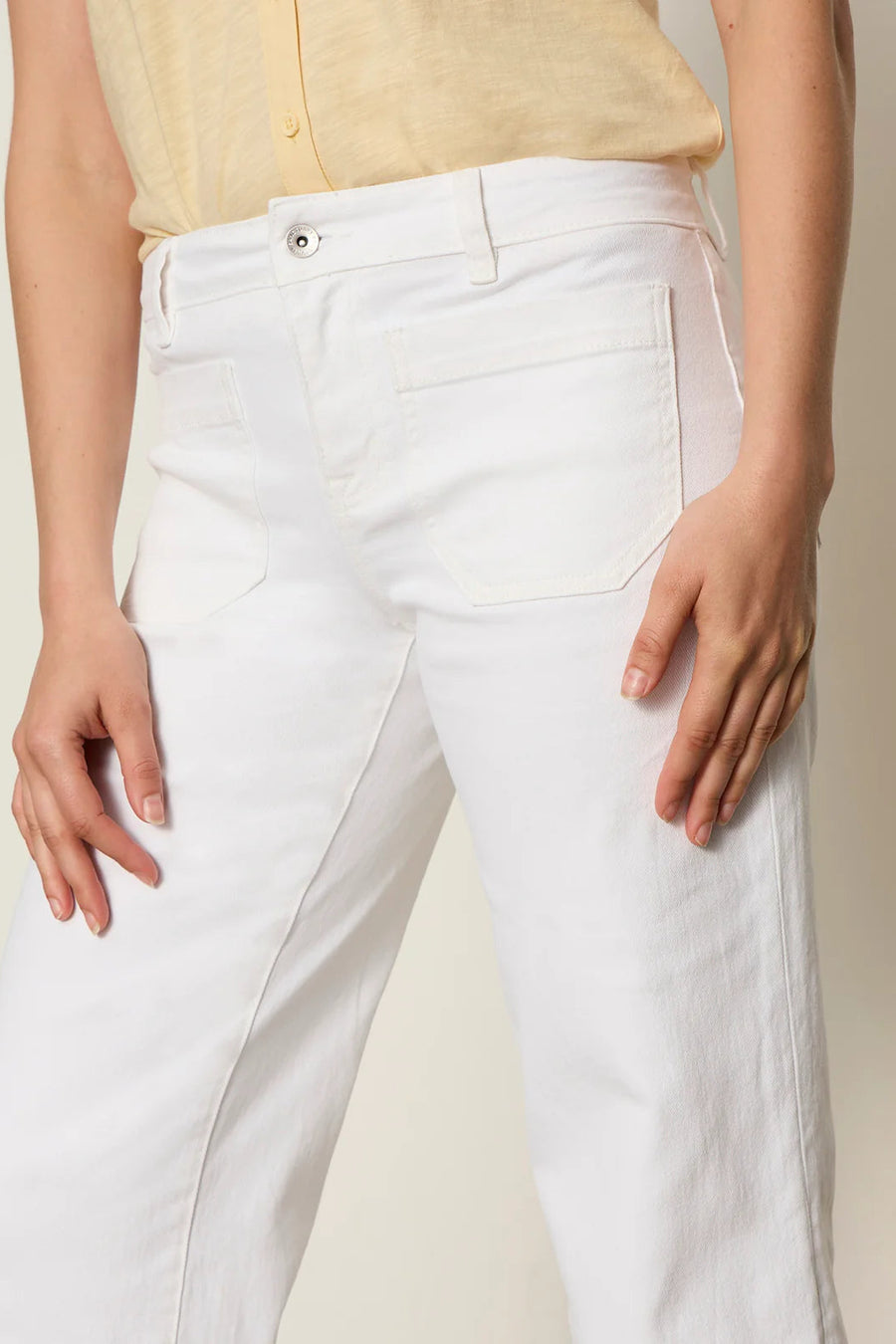 Woman wearing white high-waisted cropped straight-leg pants, detail