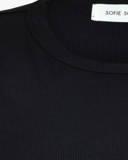Woman wearing a black short-sleeve crewneck top with a relaxed fit, detail view