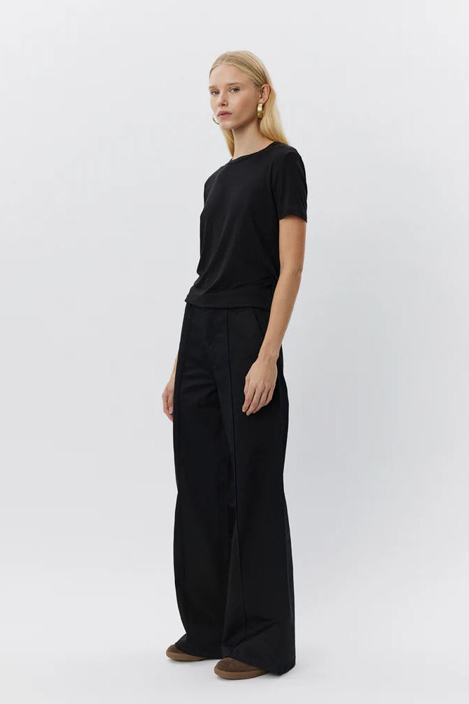 Woman wearing a black short-sleeve crewneck top with a relaxed fit ide view