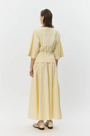 Woman wearing a pale yellow elastic-waist midi skirt with a drawstring, back