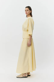 Woman wearing a pale yellow elastic-waist midi skirt with a drawstring, side