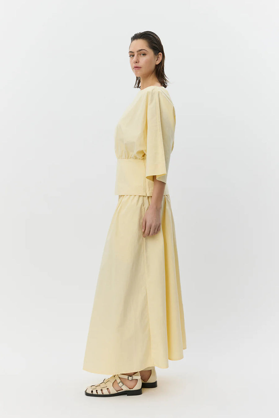 Woman wearing a pale yellow elastic-waist midi skirt with a drawstring, side