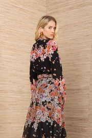 Back view of a woman wearing a black floral blouse tucked into a matching skirt