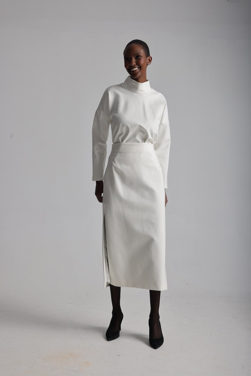 Person wearing a white outfit with a high collar and skirt on a plain background
