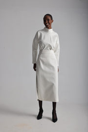 Person wearing a white outfit with a high collar and skirt on a plain background
