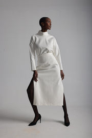 Woman wearing a white outfit with a high collar and skirt on a plain background