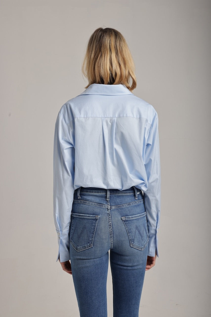 back view of woman wearing a blue collared shirt