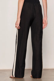 Woman wearing black lightweight  wide-leg pants with contrasting black side stripe detailing. Features a comfortable pull-on elastic waistband, relaxed fit through the leg, and a fluid full-length silhouette. Designed with side pockets and a soft drape for effortless everyday wear, back