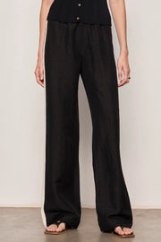 Woman wearing black lightweight  wide-leg pants with contrasting black side stripe detailing. Features a comfortable pull-on elastic waistband, relaxed fit through the leg, and a fluid full-length silhouette. Designed with side pockets and a soft drape for effortless everyday wear, front