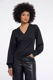 Woman wearing a black v-neck blouse. 