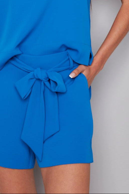 woman wearing blue vegan silk shorts with a bow belt