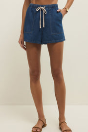 Woman wearing denim shorts in a dark blue wash with a drawstring and pockets, front view
