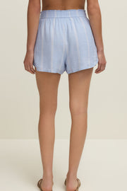 Woman wearing light blue linen short with vertical white stripes and a drawstring, back view