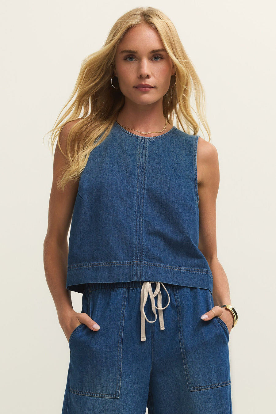 Woman wearing a denim tank top in a dark blue wash, front view
