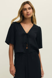 Woman wearing a black short sleeve linen top with two ties on the front, front view