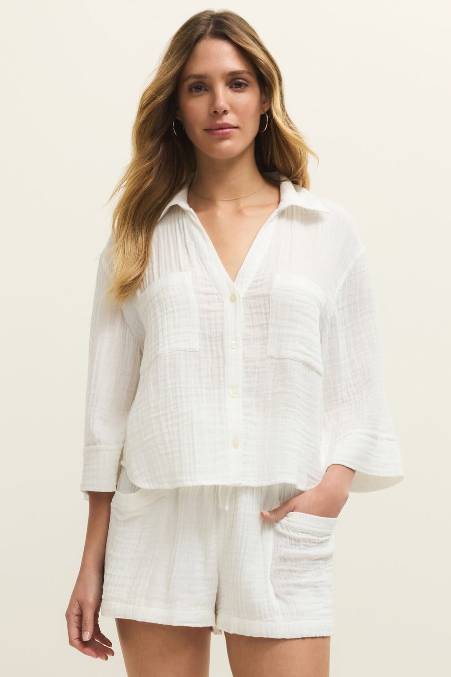 Woman wearing a white, relaxed fit button down shirt with two front pockets, front view