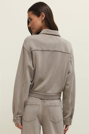 Woman wearing a taupe zip-front jacket with chest pockets, back view