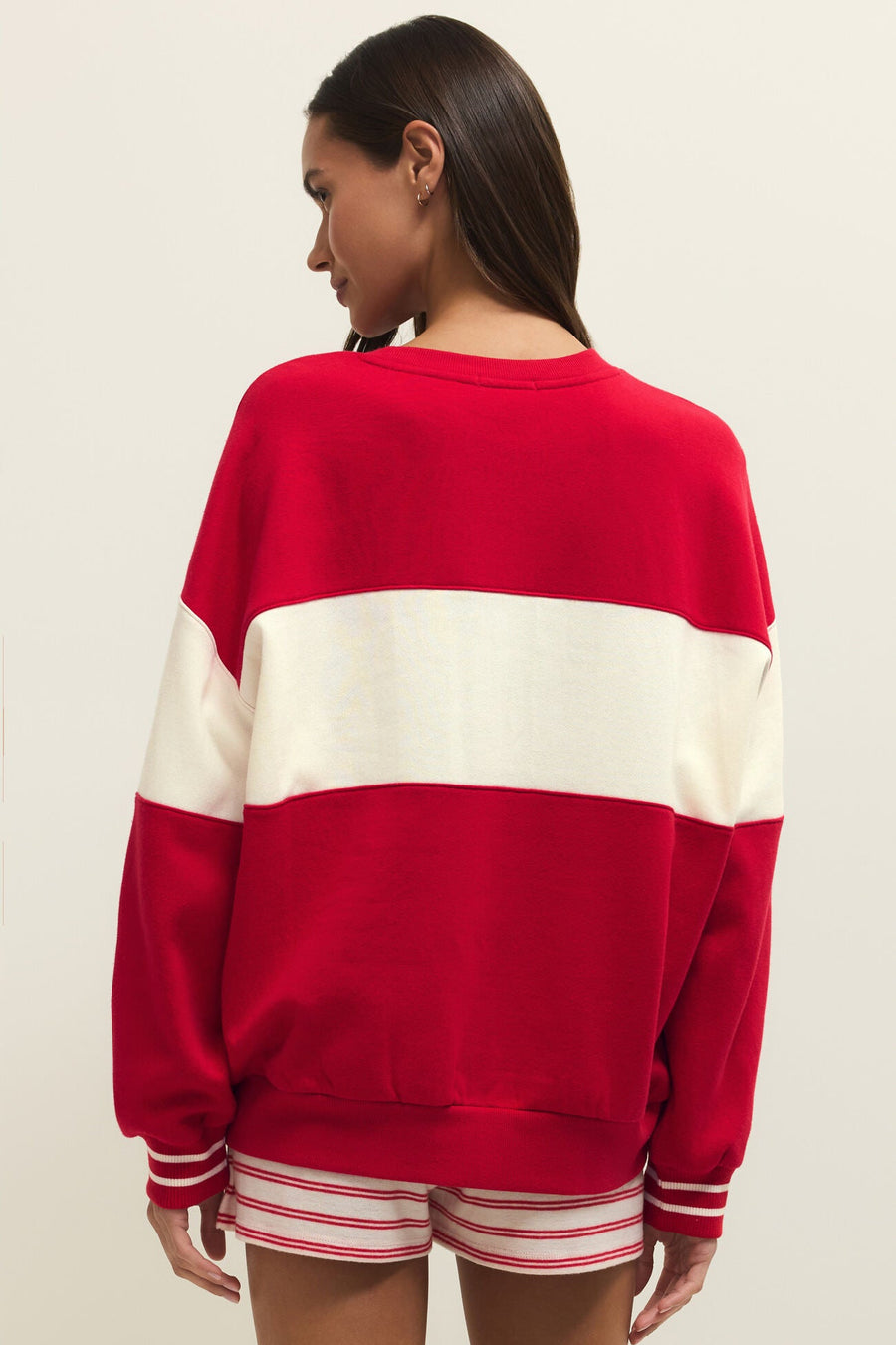 Woman wearing wearing a red and off white color block crewneck sweatshirt with the word "LOVE" written in chenille, back view