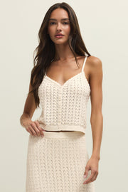 Woman wearing a cream knit camisole with buttons on the front, scalloped trim and open stitch detailing, front view