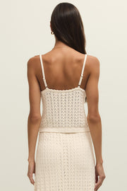 Woman wearing a cream knit camisole with buttons on the front, scalloped trim and open stitch detailing, back view