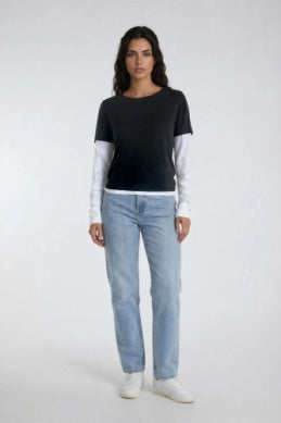 A woman modeling a black short-sleeve top layered over a white long-sleeve shirt
