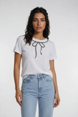 A woman modeling a white short-sleeve t-shirt with a black bow graphic on the chest