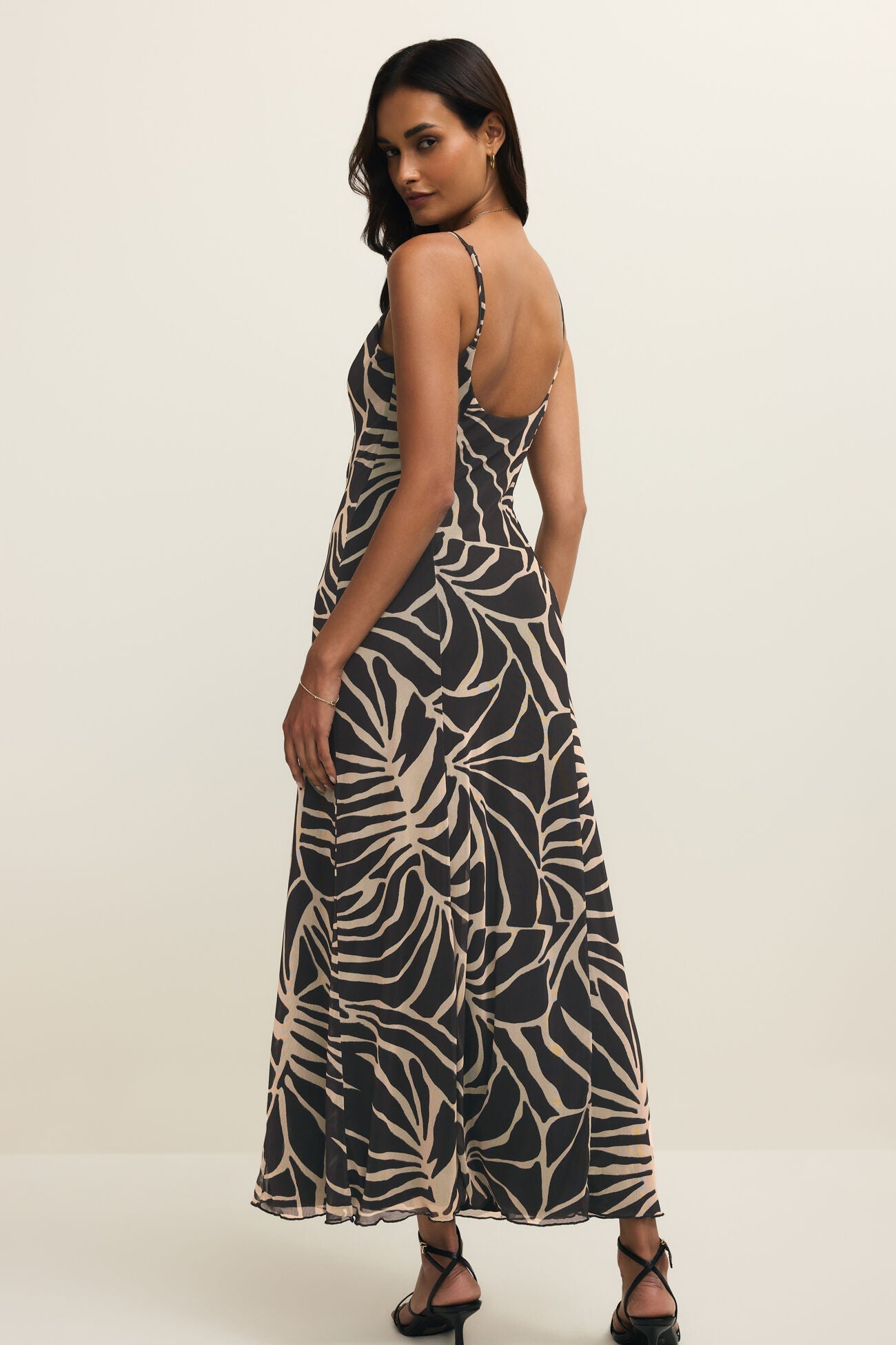 Woman wearing a long black dress with with a leaf print all over it, back view
