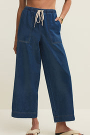 Woman wearing relaxed ankle length straight wide leg pants in a dark blue denim wash with a drawstring and pockets, front view