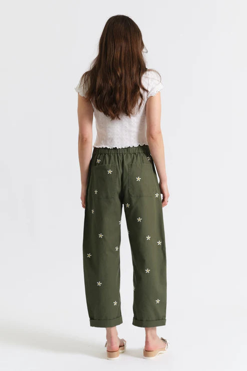 Woman wearing olive green drawstring pants embroidered with daisies, back view