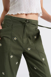 Woman wearing olive green drawstring pants embroidered with daisies, detail view