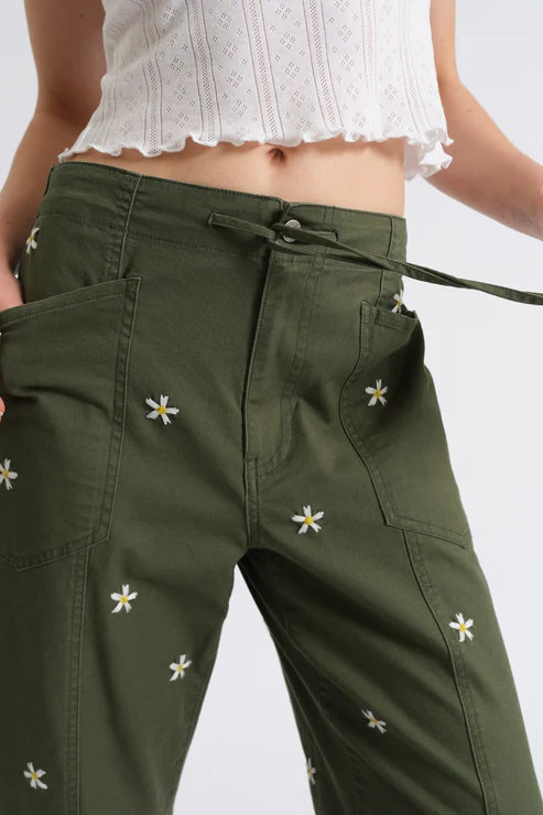 Woman wearing olive green drawstring pants embroidered with daisies, detail view