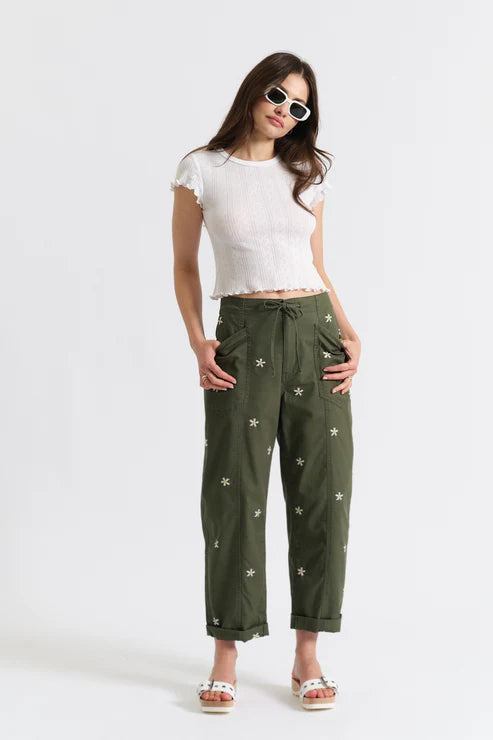 Woman wearing olive green drawstring pants embroidered with daisies, front view