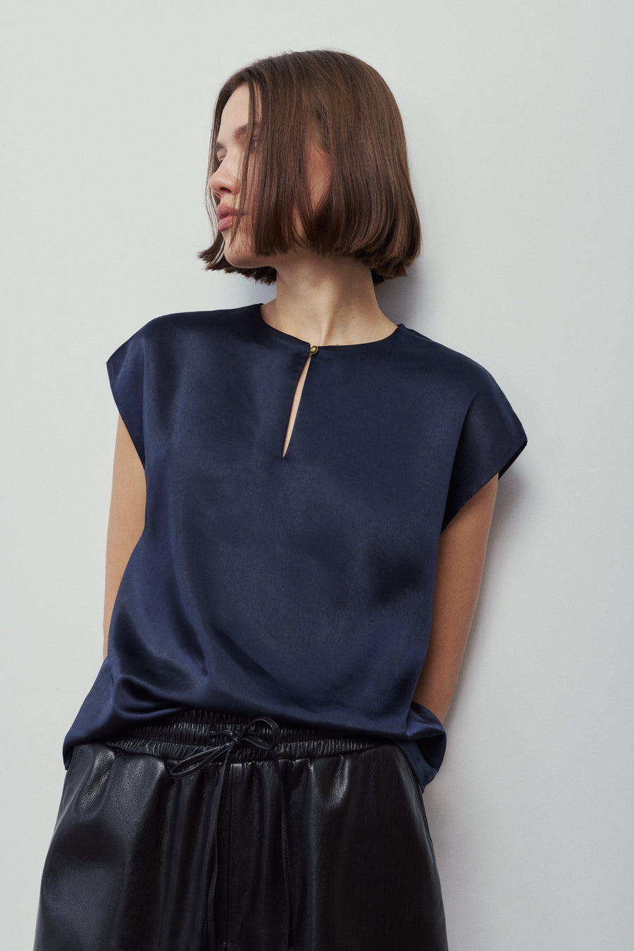 woman wearing a navy blue blouse with a gold button detail