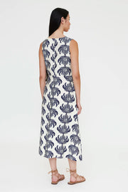 Woman wearing a sleeveless V-neck midi dress with a blue palm print and a tie waist, back view