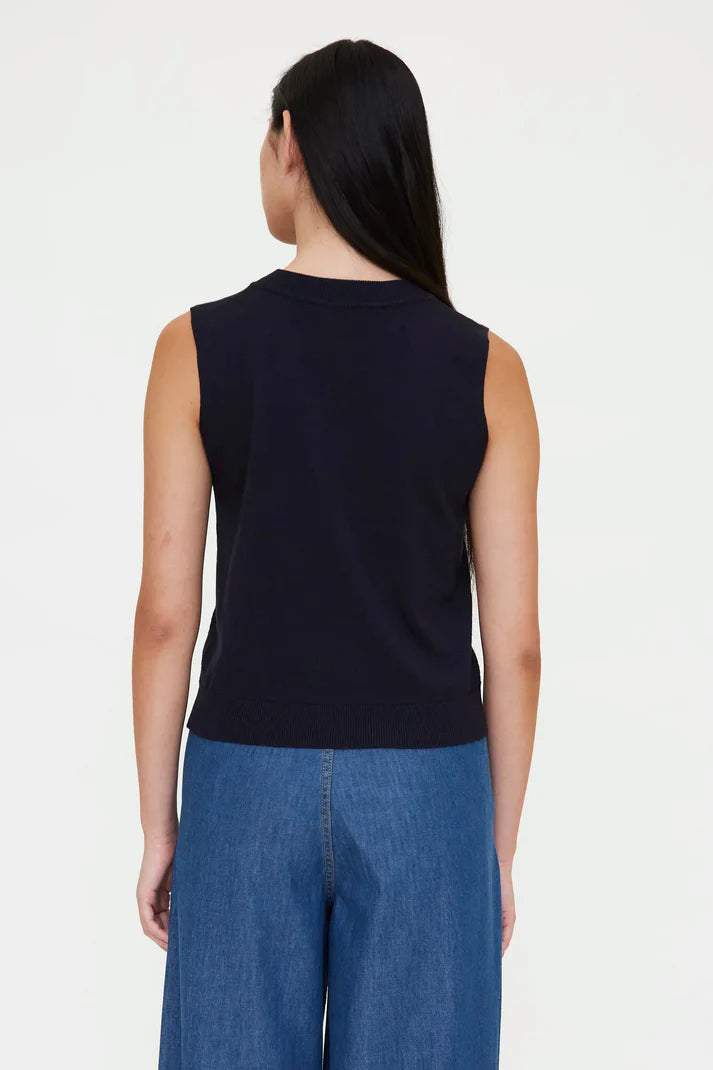 Woman wearing a navy sleeveless knit top with a crew neckline, back view