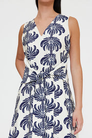 Woman wearing a sleeveless V-neck midi dress with a blue palm print and a tie waist, detail view