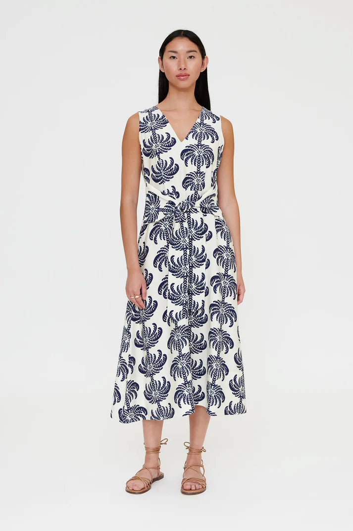 Woman wearing a sleeveless V-neck midi dress with a blue palm print and a tie waist, front view