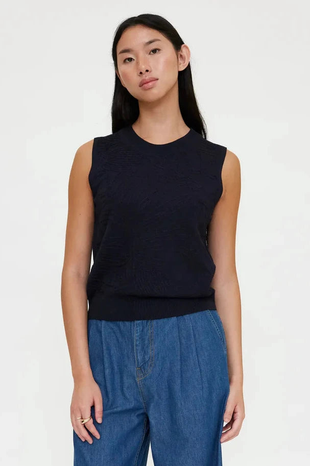 Woman wearing a navy sleeveless knit top with a crew neckline, front view